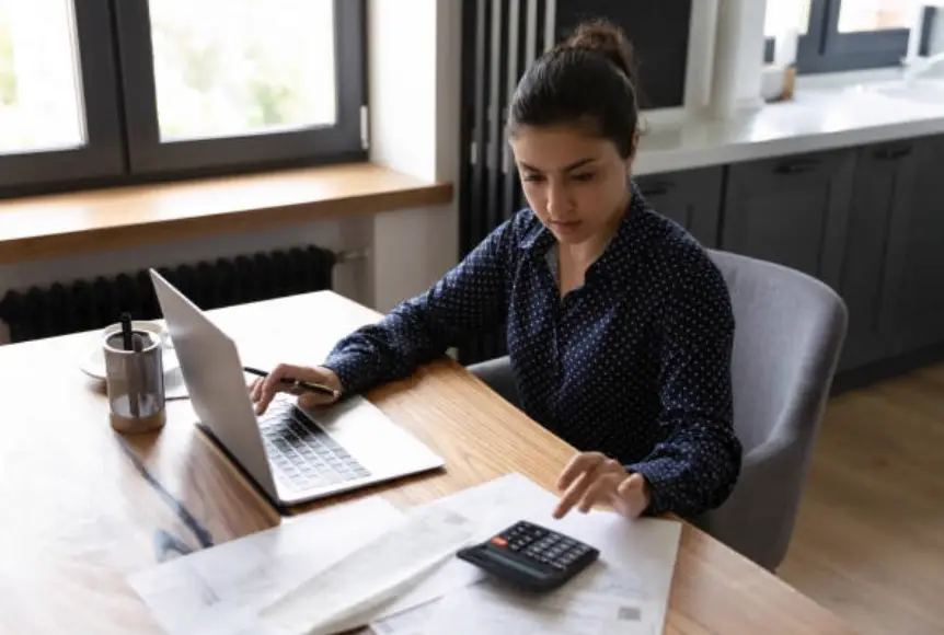 Person with a laptop, calculator and papers making bookkeeping entries