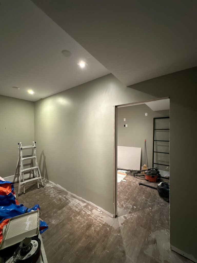 Interior view of a room under renovation, featuring a ladder and tools on the wooden floor.