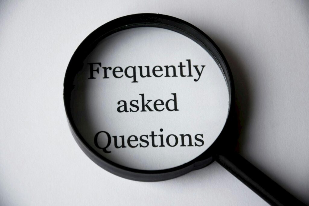 FAQ Close-up of a magnifying glass focusing on the phrase 'Frequently Asked Questions'.